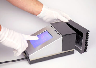 Technician placing a foil sample onto the TIR100-2 emissometer aperture for a repeatable emissivity measurement.