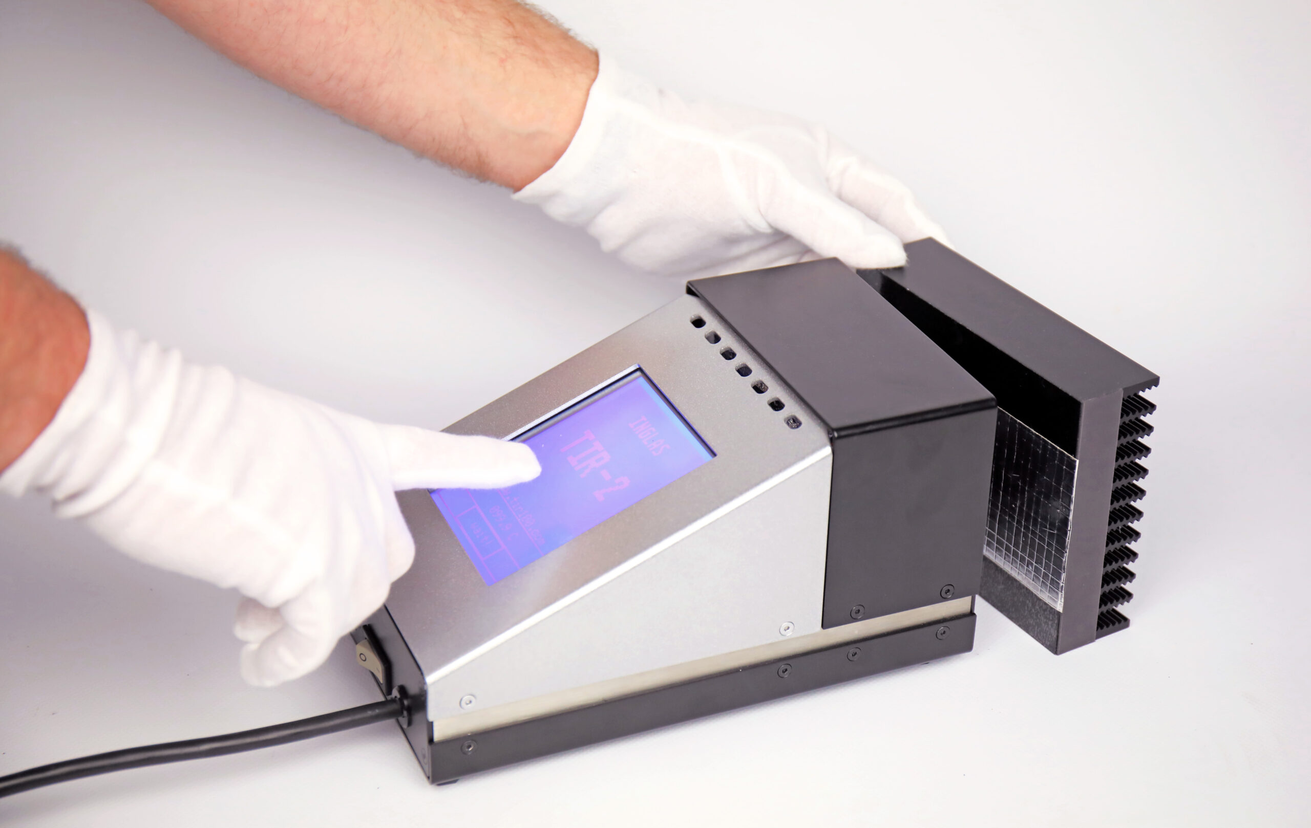 Technician placing a foil sample onto the TIR100-2 emissometer aperture for a repeatable emissivity measurement.
